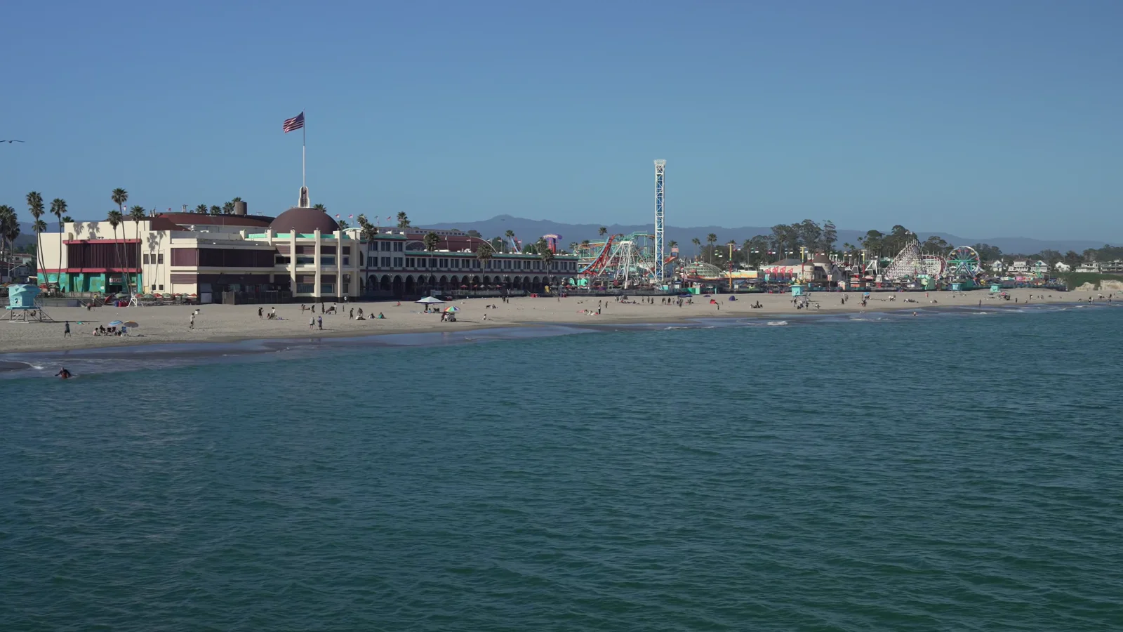 An aerial view over the Santa Cruz Beach Boardwalk, its rides, beach and Pacific coastline